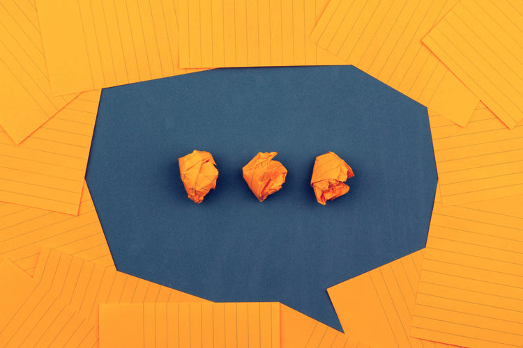 A photo of paper laid out to form the shape of a speech bubble with ellipsis inside.